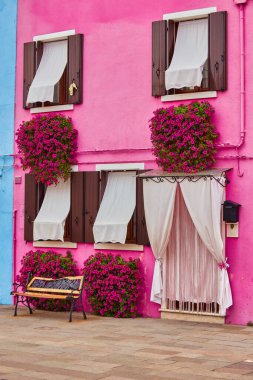 Evin kırmızı cephesinde çiçek olan kapı ve pencere. Burano Adası, Venedik, İtalya 'da renkli mimari.