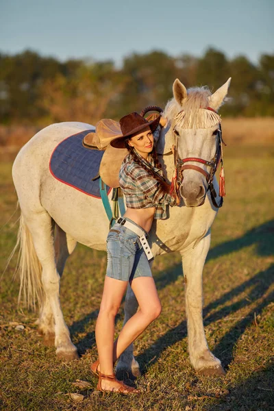 Happy cowgirl in hat hugging her horse