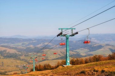 Resimli sonbahar dağlarının arka planında güneşli bir günün sıcacık parıltısında güneşlenen eski teleferik.. 