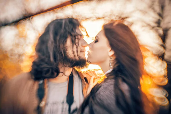 couple deeply in love shares a tender kiss against the backdrop of autumn. The strong and unconventional background blur, achieved with a specialized lens