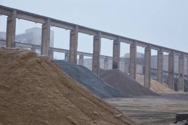 Kum ve çakıllar için bir depolama alanı birikiyor, sonbahar mevsimi boyunca sisle kaplanıyor. Düzenleme sisli arkaplana karşı desenli bir manzara yaratır..