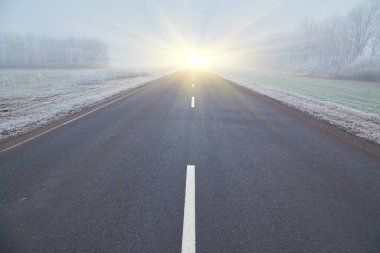 Buzlu ağaçlar, sisli bir atmosfer ve kaybolan asfalt bir yol ile kış sabahı. Uzağa doğru asfalt bir yol uzanıyor, sisin içinde kayboluyor, esrarengiz bileşimi ekliyor..