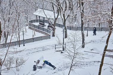 Karla kaplı ağaçlar ve şehir Park banklar. Günbatımı