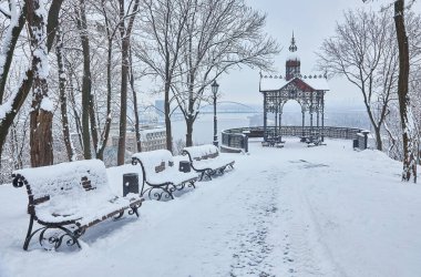 Karla kaplı ağaçlar ve şehir Park banklar. Günbatımı