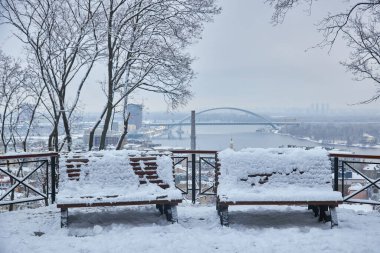 Karla kaplı ağaçlar ve şehir Park banklar. Günbatımı