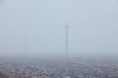 Sis kaplı tarla uzak mesafelere doğru uzanıyor, yeryüzü buzla kaplanıyor, dingin ve büyüleyici bir manzara yaratıyor..