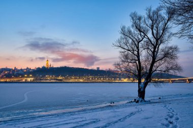 Kışın büyüsünü kucaklayan bu fotoğraf Kyiv 'deki donmuş Dnipro Nehri' nin dingin güzelliğini yansıtıyor. Simgesel Kyiv Pechersk Lavra ufku süslüyor..