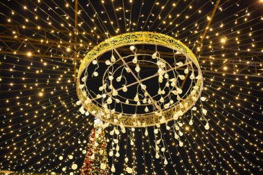 Çelengin ışıkları evi ve Noel ağacını süslüyor, dalın üzerinde kırmızı parıldayan bir top var. Yılbaşı arifesinde akşam kentinde Noel ağacı. Noel havası.