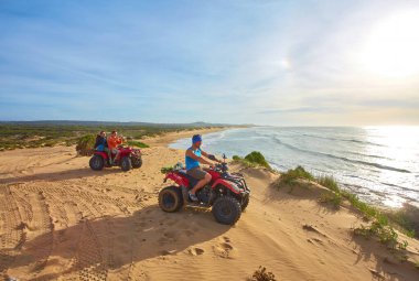 Bir grup turist Essaouira 'nın okyanus kıyısında bisiklet sürerek manzaralı sahile karşı maceralı bir manzara yaratıyorlar.