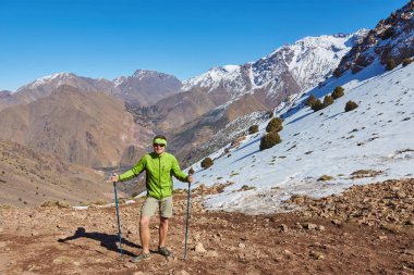 Atlas Dağları 'ndan geçen bir turist, karla öpülmüş zirvelere bakarak bu sakin dağ kaçışının ihtişamını yakalıyor..