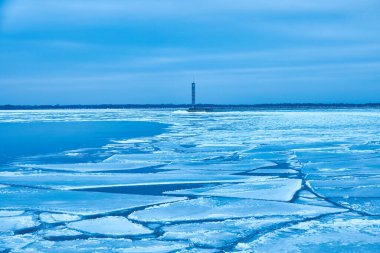 Huzurlu bir su deposu, canlı mavi bir buz ve ıssız bir deniz feneri olan büyüleyici bir kış sahnesi..