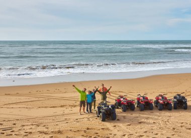 Bir grup turist Essaouira 'nın okyanus kıyısında bisiklet sürerek manzaralı sahile karşı maceralı bir manzara yaratıyorlar.