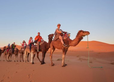 Sahra Çölü 'nde, Fas' ta deveye binen, gülümseyen turistler..