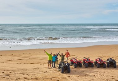Bir grup turist Essaouira 'nın okyanus kıyısında bisiklet sürerek manzaralı sahile karşı maceralı bir manzara yaratıyorlar.