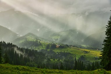Dağ manzarası, güneş ışığı bulutların ve sislerin arasından geçti ve dağ çayırlarını aydınlattı. Doğal güzellik.