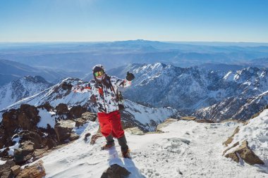Dağın tepesindeki dağcı ya da dağcı. Zirveye ulaşan bir dağcının başarısı. Alp dağları manzarasında açık hava macera sporları. Güneşli bir gün ve zirvedeki bir dağcı.