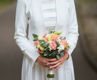 Gelinin buketini tutan zarif eller düğün çiçeklerinin güzelliğini gözler önüne seriyor..