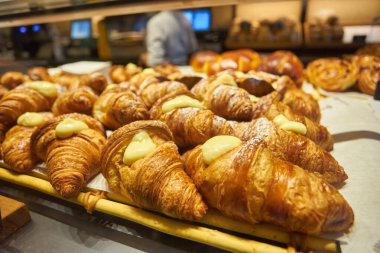 Kahve dükkanındaki cam rafta kruvasan ve pasta var..