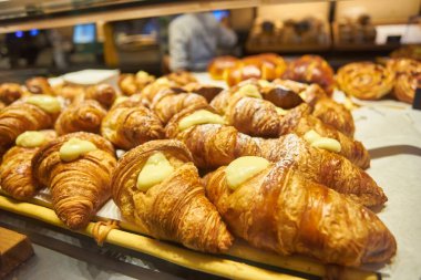 Yakın görüş - yeni pişmiş kruvasanların tezgahta, markette, kafede veya fırında satışı. Tatlı, pasta, kahvaltı, tatlı yemek ve geleneksel Fransız mutfağı konsepti.