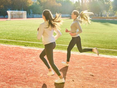Atletizm Stadyumu yolda, sıcak yaz sabah sırasında açık hava koşu kadın çalışan iki fitness.