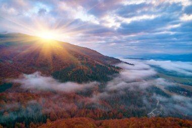 Sis şafakta dağların üzerine yayılır. Güneş ufuktan doğuyor. Sabah Ukraynalı Karpatlar. Hava aracı görünümü.
