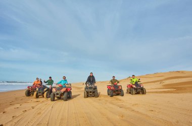 Bir grup turist Essaouira 'nın okyanus kıyısında bisiklet sürerek manzaralı sahile karşı maceralı bir manzara yaratıyorlar.