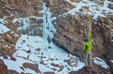 Jebel Toubkal tepesi, Atlas dağları, Fas yakınlarındaki donmuş bir şelalenin yanında yürüyüş yapan biri.