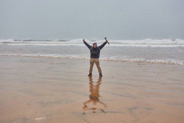 Fas 'ta Atlantik Okyanusu kıyısında turistler. Yağmurlu bir hava. İnsanlar okyanusla ilk kez karşılaştıkları için mutlular..