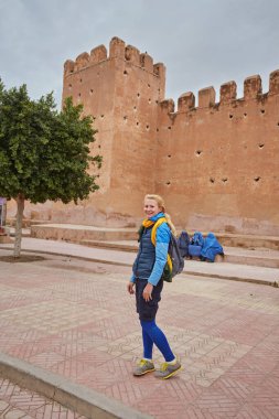 A traveler is photographed in front of the fortress wall of Turandot, Morocco clipart