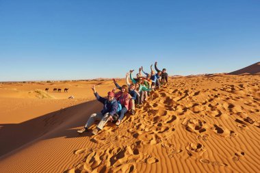 Bir grup turist Sahra Çölü 'nde neşeli pozlar vererek anları yakalıyor.