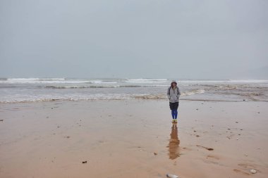 Fas 'ta Atlantik Okyanusu kıyısında turistler. Yağmurlu bir hava. İnsanlar okyanusla ilk kez karşılaştıkları için mutlular..
