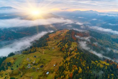 Sis şafakta dağların üzerine yayılır. Güneş ufuktan doğuyor. Sabah Ukraynalı Karpatlar. Hava aracı görünümü.