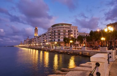 Bari, İtalya 'da deniz önü ve gezinti güvertesinde boş bank ve lamba direkleri. Romantik, sakin, rahatlatıcı bir akşam. Güneş batıyor.