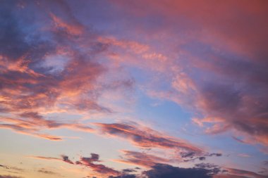 Yumuşak pembe, mor ve mavi renklerle dolu güzel bir günbatımı gökyüzü. Bulutlar batan güneş tarafından aydınlatılır. Huzurlu ve sakin bir atmosfer yaratır. Arkaplan ve tasarımlar için idealdir..