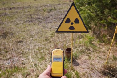 Radyasyon detektörü Ukrayna 'nın Çernobil Yasak Bölgesi' nde radyasyon uyarısı işareti yakınlarında yüksek değerler gösteriyor..