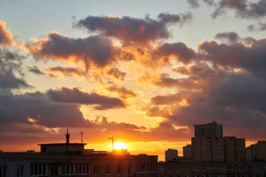 Göz kamaştırıcı bir gün batımı gökyüzü uzak bir şehrin silueti üzerinde pembe, turuncu ve mavi bulutlarla dolu. Canlı renkler ve yumuşak ışık huzurlu ve dinamik bir şehir atmosferi yaratır..