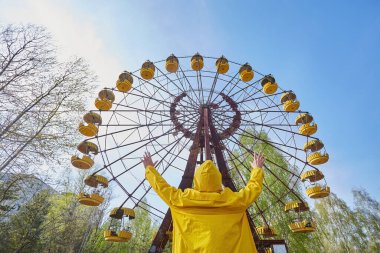 Pripyat 'ın terk edilmiş lunaparkındaki hareketsiz dönme dolabın önünde tek başına duran, 1986 Çernobil faciasının ve şehrin neşesinin kayboluşunun akıllardan çıkmayan bir hatırlatıcısı..