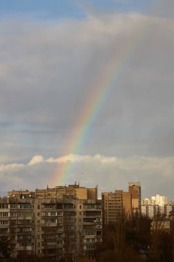 Bir yağmur fırtınasından sonra gökyüzünde canlı bir gökkuşağı belirir. Yumuşak ışık bulutları ve binayı aydınlatıyor. Fırtına sonrası sakin bir şehir manzarası yaratıyor..