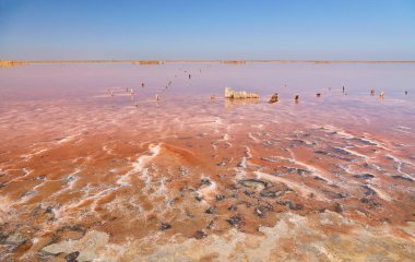 Uçsuz bucaksız, pembe tuzlu göl mavi gökyüzünün altında ince bulutlu.
