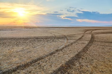Göl yatağının kuru yüzeyinde veya bulutlu bir gökyüzünün altında tekerlek izleri kıvrılıyor..
