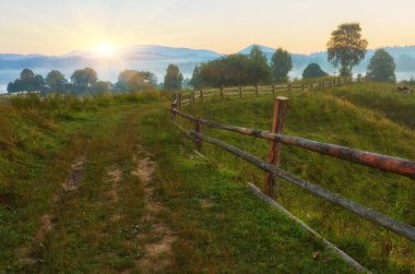 Bahçesinde eski ahşap bir ev olan dağlık kırların sisli sonbahar sahnesi. Karpat Dağları 'nın sakin sabah manzarası, Ukrayna, Avrupa. Kırsal konseptin güzelliği.