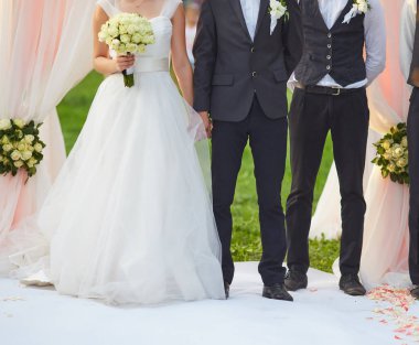 Bir gelinin elinde bir buket beyaz gül ve siyah takım elbiseli bir damadın düğün törenlerinde el ele tutuşması, aşkı ve birlikteliği simgeliyor..