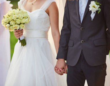 Bir gelinin elinde bir buket beyaz gül ve siyah takım elbiseli bir damadın düğün törenlerinde el ele tutuşması, aşkı ve birlikteliği simgeliyor..