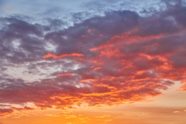 Canlı turuncu, mor ve pembe renkleriyle dramatik ve renkli günbatımı gökyüzü. Yumuşak bulutlar batan güneş tarafından aydınlatılır..