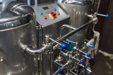 Bira fabrikasındaki parlak paslanmaz çelik ekipmanların yakından görüntüsü. Borular, vanalar, tanklar ve kontrol paneli de dahil. Sanayi geçmişi.