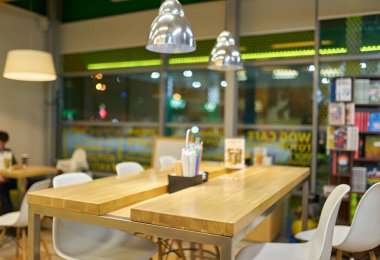 Modern bir kafe ya da restoranın içi bulanık, masaları, sandalyeleri ve asılı lambaları gösteriyor. Yumuşak, odak dışı arkaplan.