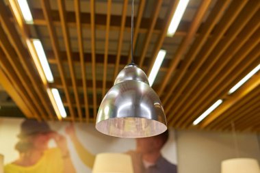 Modern bir kafe ya da restoranın içi bulanık gümüş lambalar ve tavan lambaları asmaya odaklı. Sıcak, davetkar atmosfer.