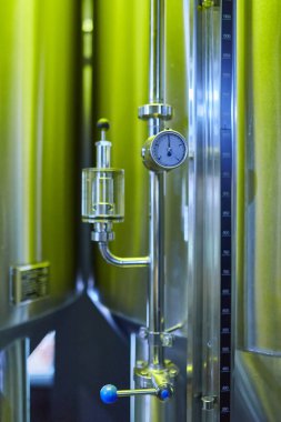 Basınç göstergesi ve görüş camı olan paslanmaz çelik bir bira tankının yakın çekimi..