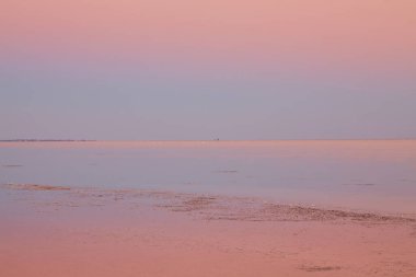 Geniş, sakin tuz gölü alacakaranlıkta gökyüzünün pembe ve mavi tonlarını yansıtıyor..
