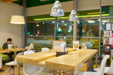 Modern bir kafe ya da restoranın içi bulanık, masaları, sandalyeleri ve asılı lambaları gösteriyor. Yumuşak, odak dışı arkaplan.